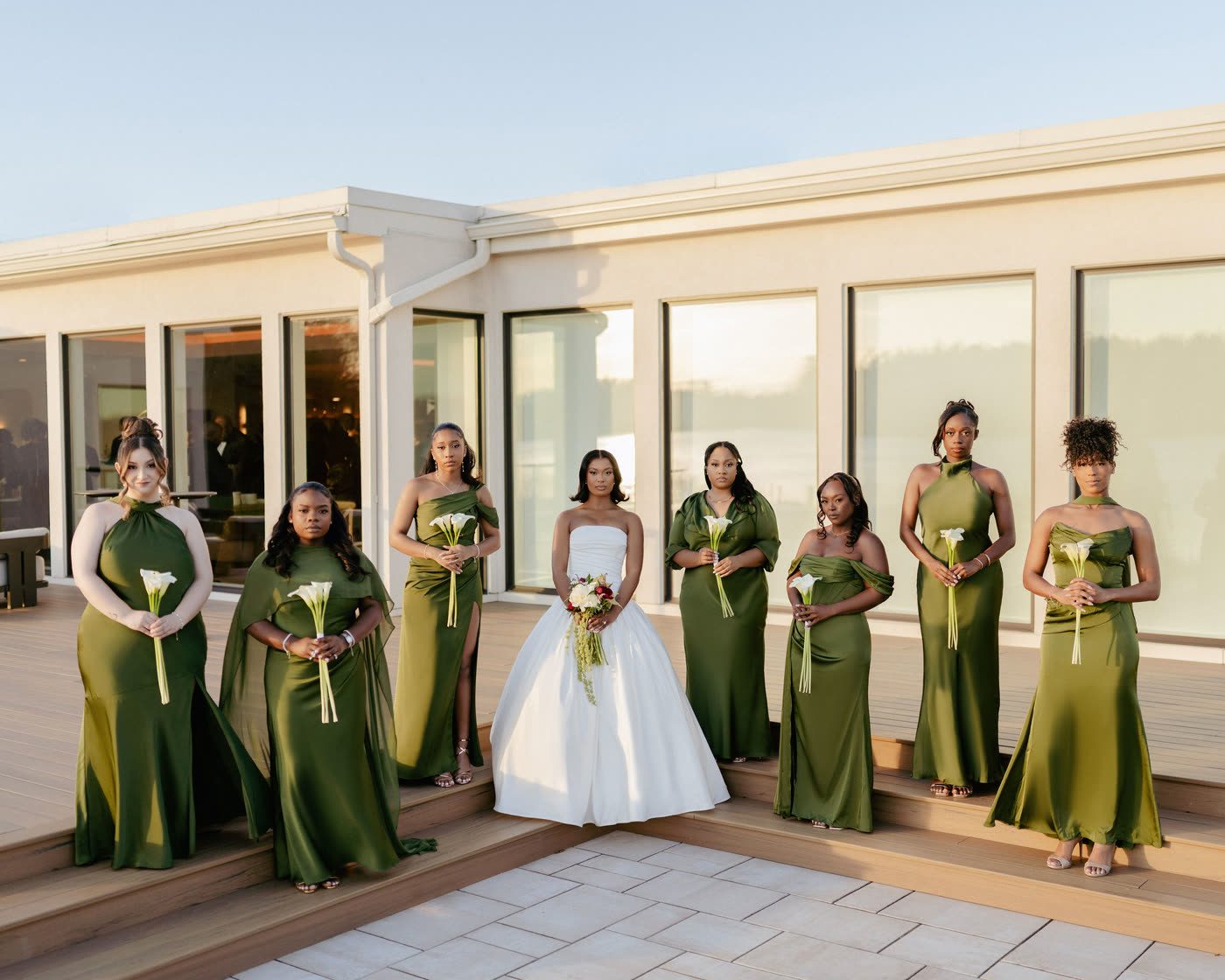 Bride and bridesmaids in olive green holding calla lilies at golden hour
