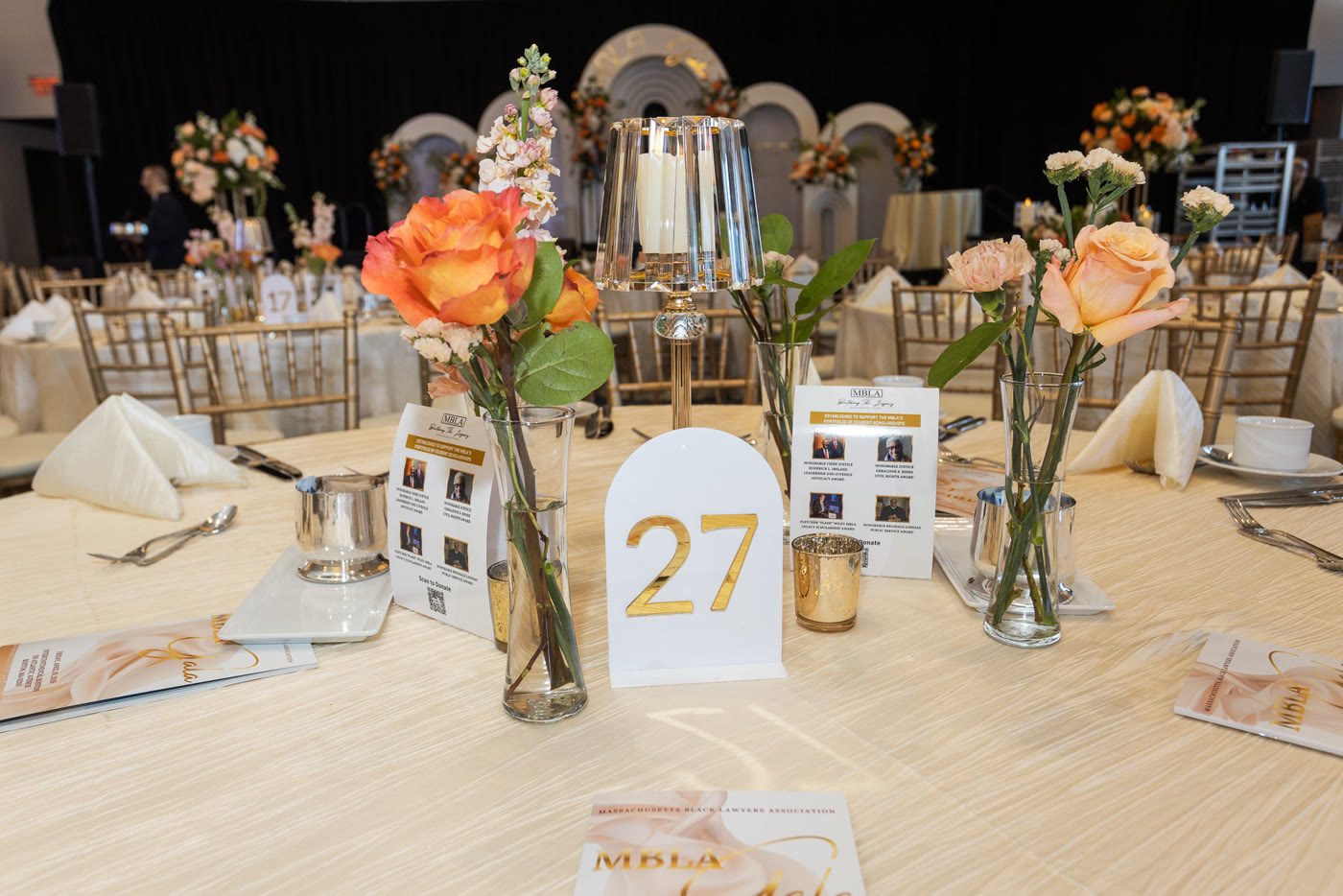 Peach bud vases and gala programs on a linen table