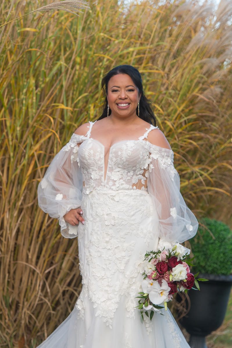 Bride holding a bouquet of burgundy roses, blush peonies and white orchids