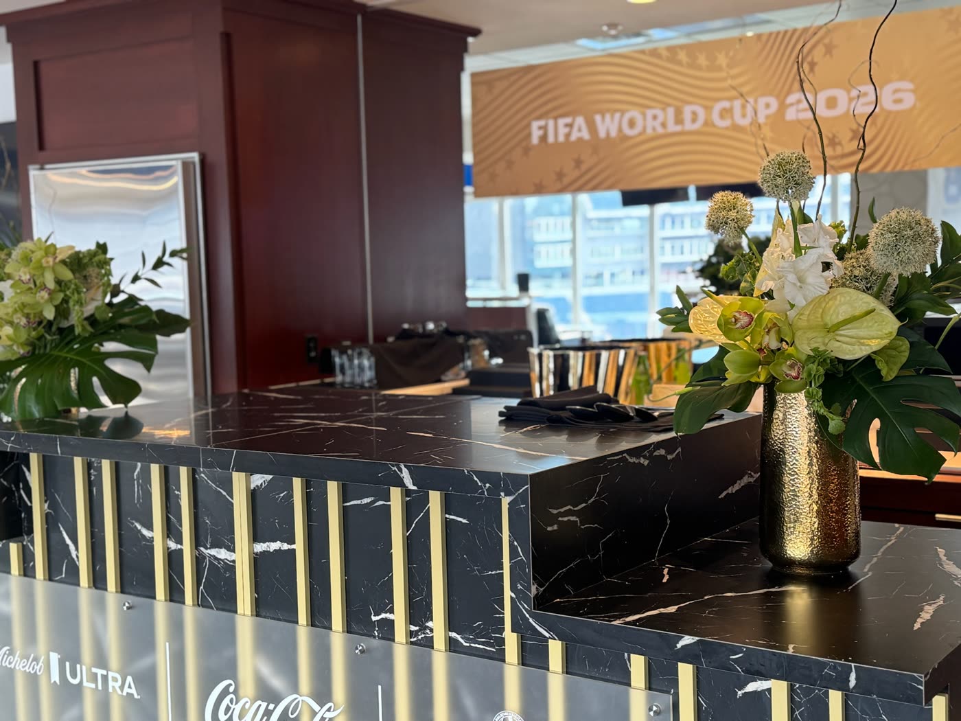 Marble suite bar lined with gold vase arrangements beneath the FIFA World Cup wall