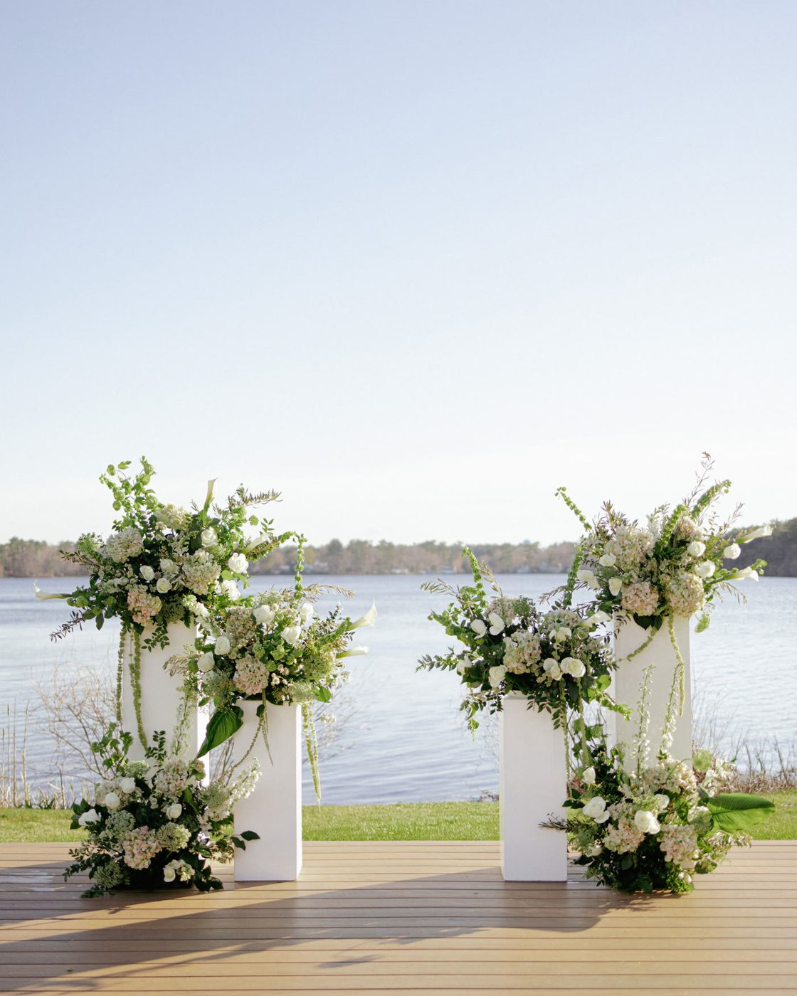 White ceremony pillars at the lakeside altar