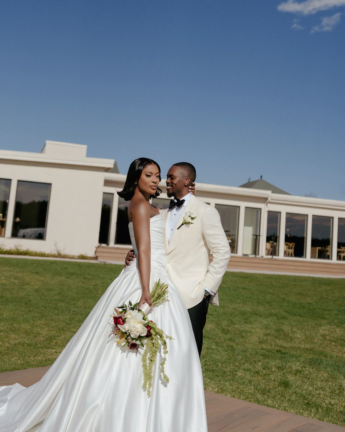 Bride and groom outside the venue, bouquet in hand