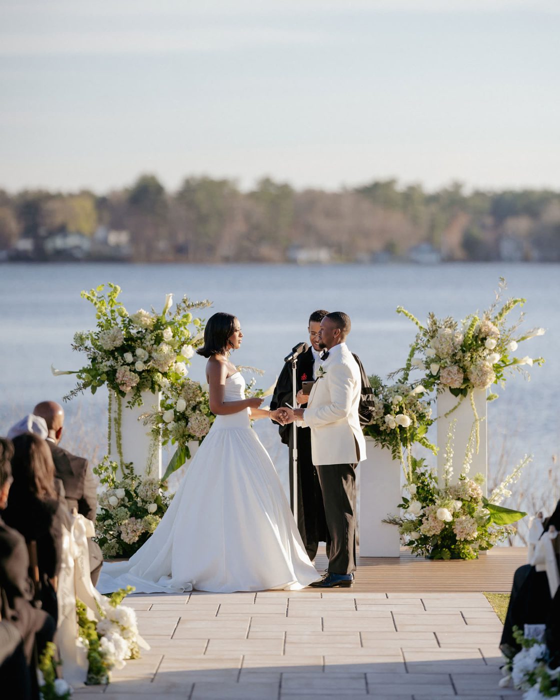 Lakeside ceremony altar with white floral pillars in golden light