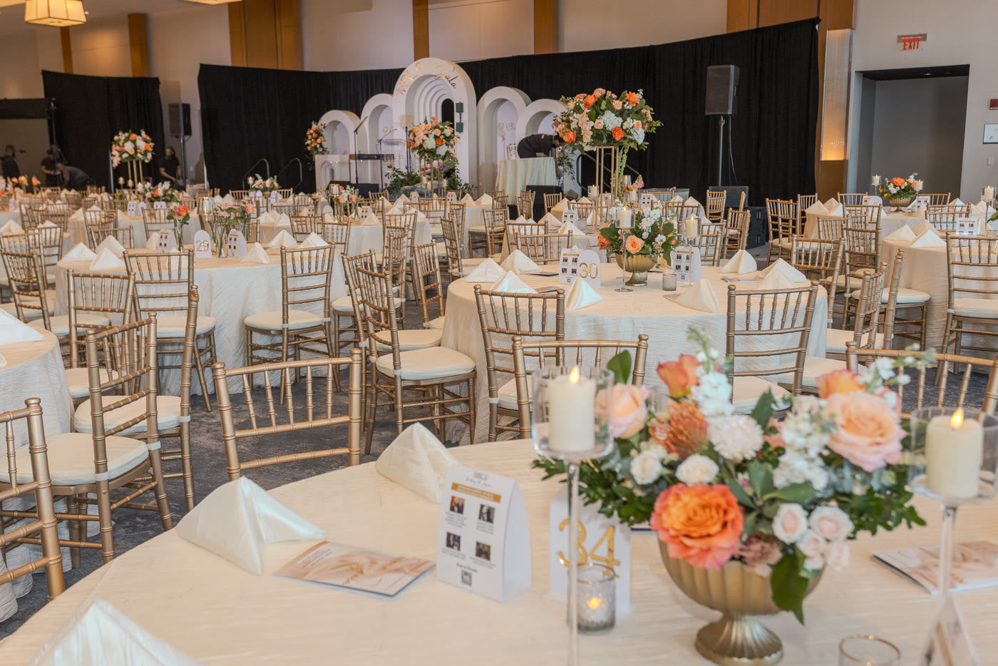 Arched stage and peach centerpieces across the ballroom