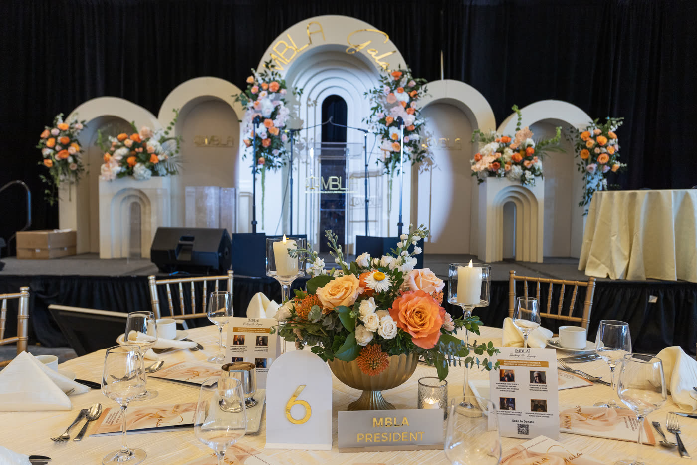 Gala stage with arched backdrop and peach florals, centerpiece in the foreground
