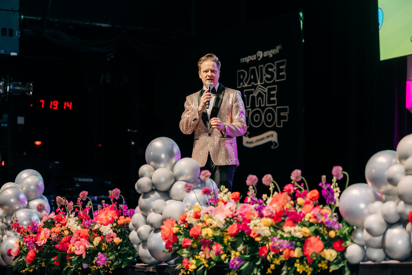 Benefit stage framed by silver balloons and technicolor florals