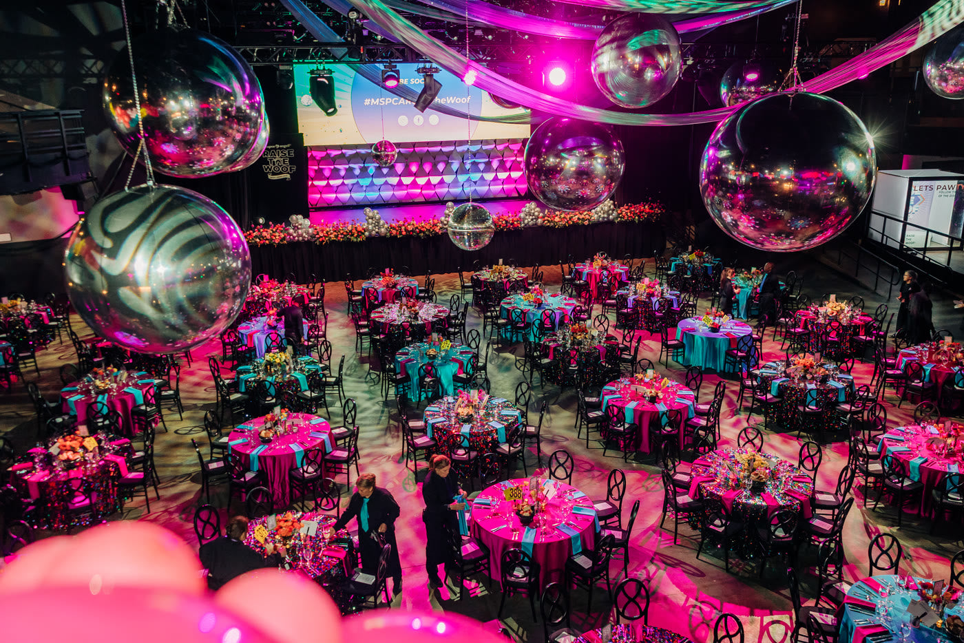 Disco balls over a room of pink and teal tables