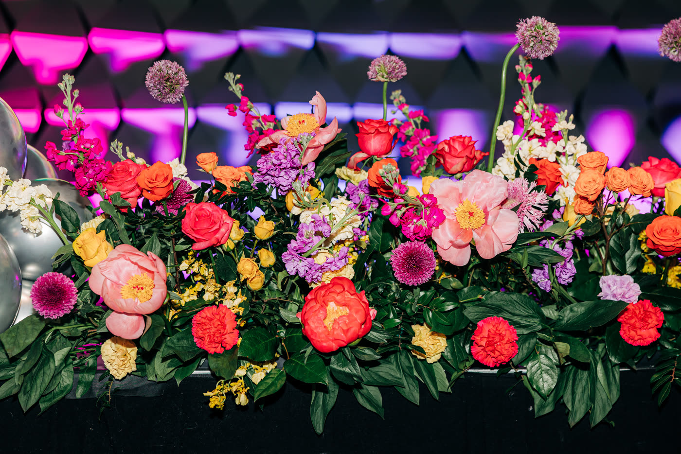 Technicolor floral runner of peonies, roses and alliums along a stage