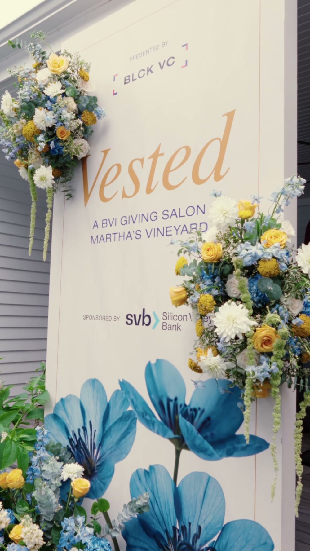 The Vested giving-salon sign on Martha&rsquo;s Vineyard, framed in blue and yellow blooms