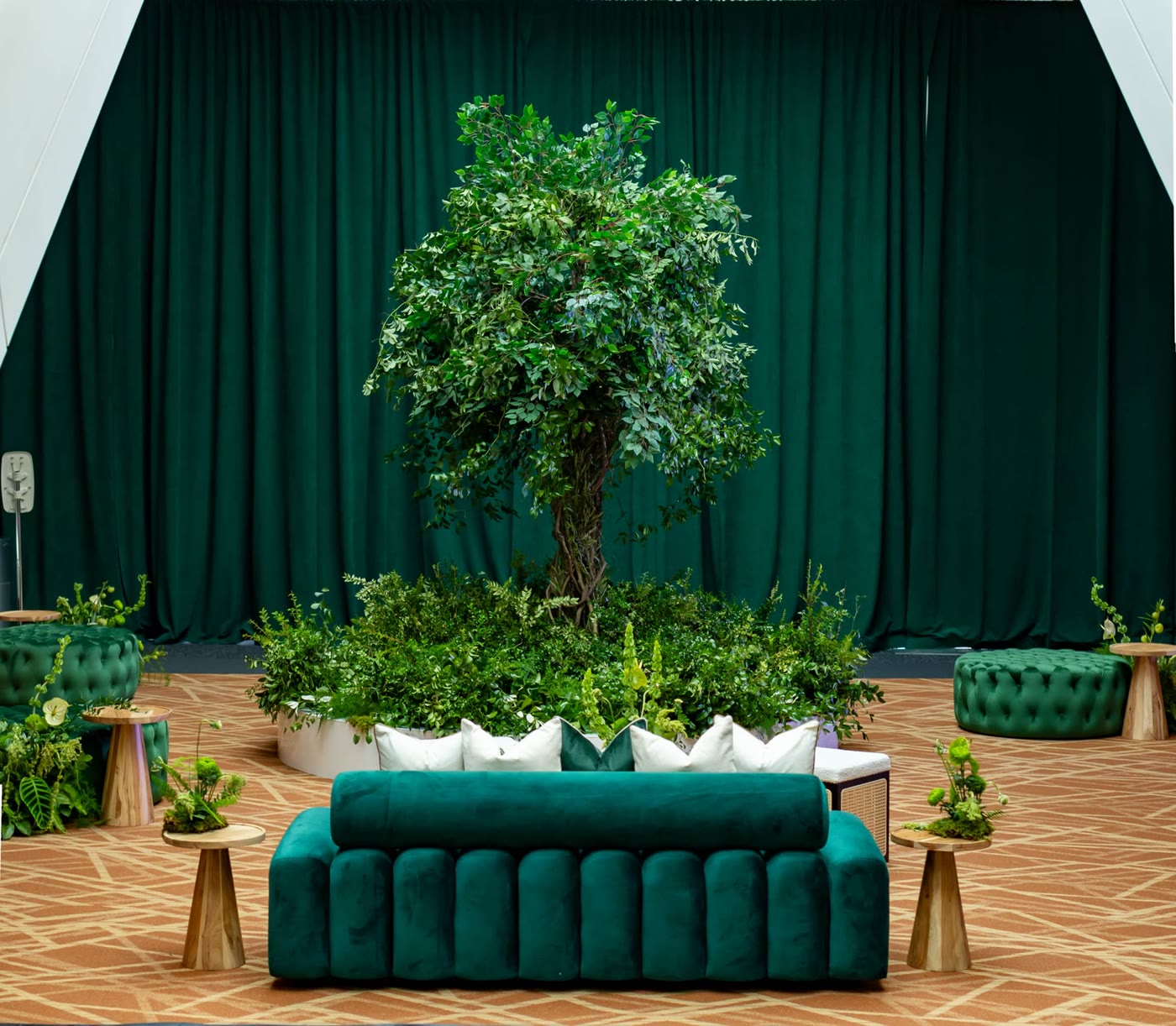 A full tree installation ringed in greenery under emerald drapes