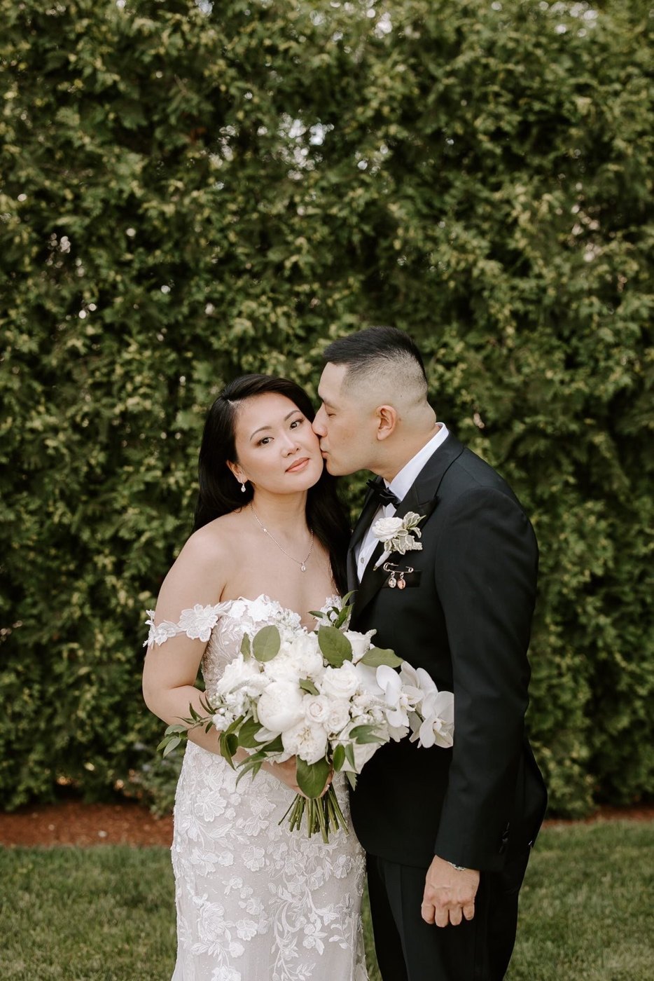 Debbie and Roger against the greenery, bouquet in hand