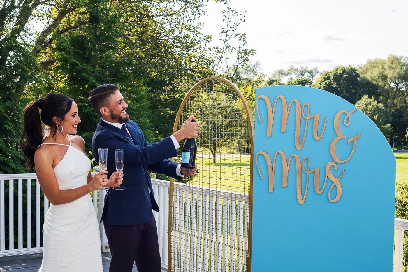 Melissa and Marc popping champagne at the Mr & Mrs arch