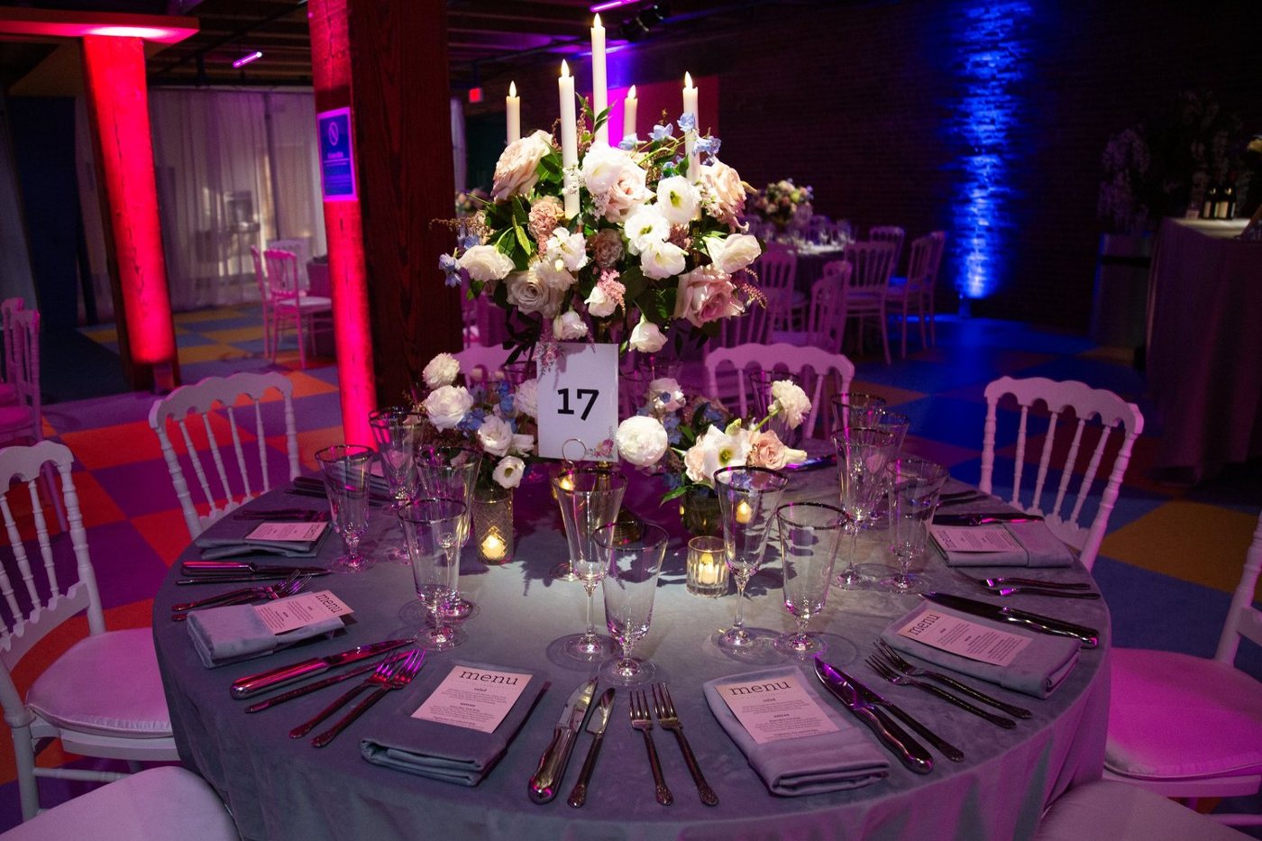 A candlelit gala table with low white and blush centerpieces