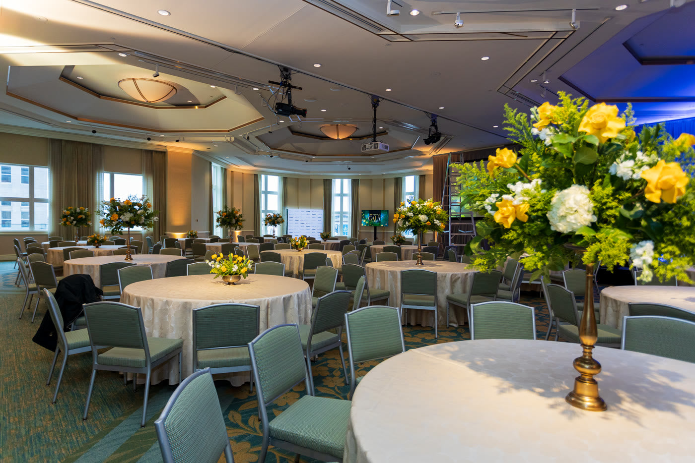 Ballroom washed in violet light, yellow centerpieces glowing
