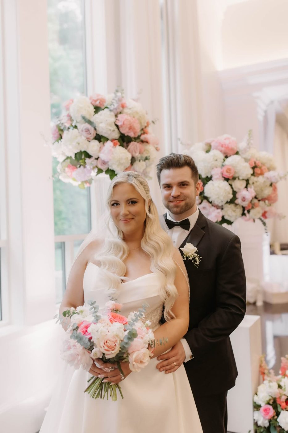 Newlyweds framed by blush and cream arrangements